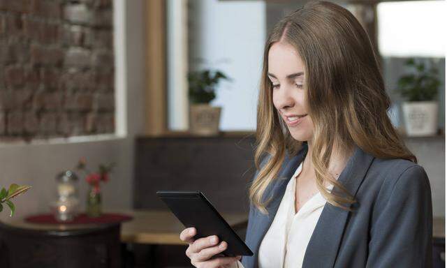 Young woman in a coffee shop looking at her e book model released Symbolfoto property released PUBLI