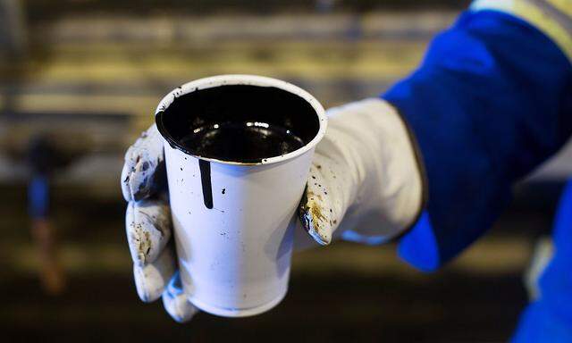 FILE PHOTO: A worker holds a cup of heavy oil south of Fort McMurray