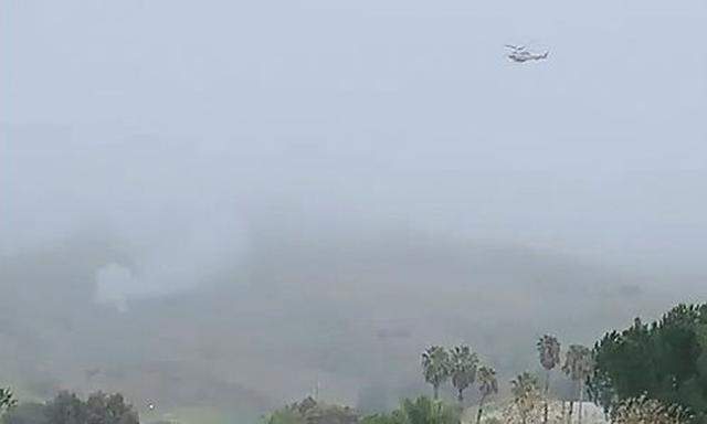 Smoke rises amid foggy weather from the site of a helicopter crash that killed former NBA star Kobe Bryant along a hillside in Calabasas