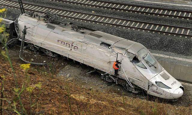 An official inspects the train engine amongst the wreckage of a train crash near Santiago de Compostela