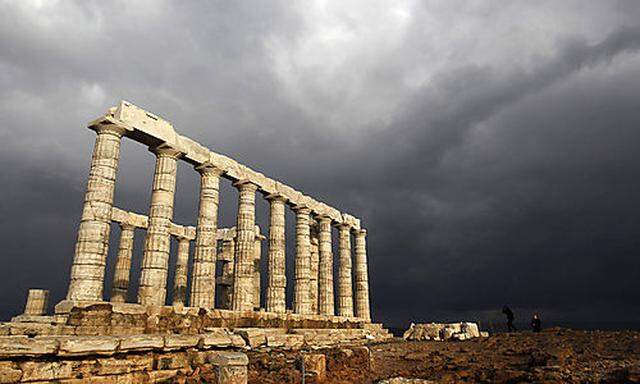 Tourists walk next to the ruins of the 5th century B.C. Temple of Poseidon at Cape Sounion, south of 
