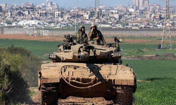 Ein israelischer Panzer an der Grenze zum Gazastreifen. Auf der palästinensischen Seite sind zahlreiche Gebäude zerstört.