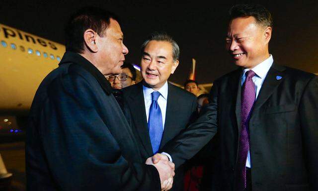 President of the Philippines Rodrigo Duterte shakes hands with Chinese ambassador to the Philippines Zhao Jianhua, as Chinese Foreign Minister Wang Yi looks on, at airport in Beijing