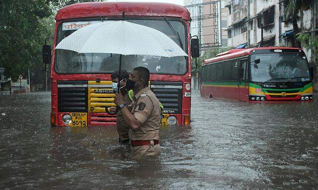 News Bilder des Tages May 17, 2021, Mumbai, India: A policeman helps a public transport driver to cross a flooded street