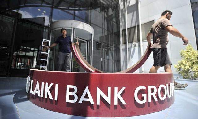 Workmen dismantle a sign of the Cyprus Popular Bank at its headquarters in the Cypriot capital Nicosia