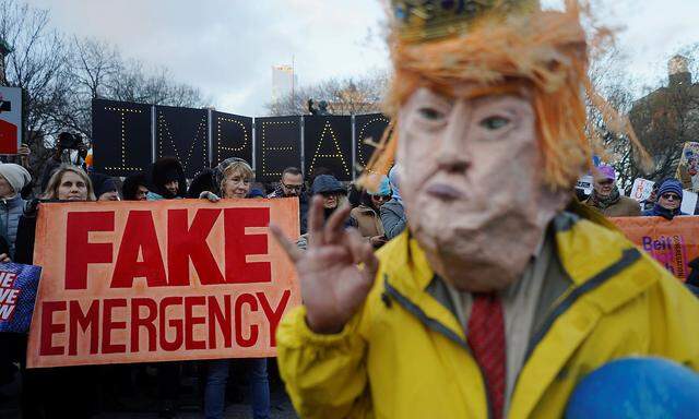 Protesters hold signs during a demonstration against U.S. President Donald Trump on Presidents' Day in Union Square, New York