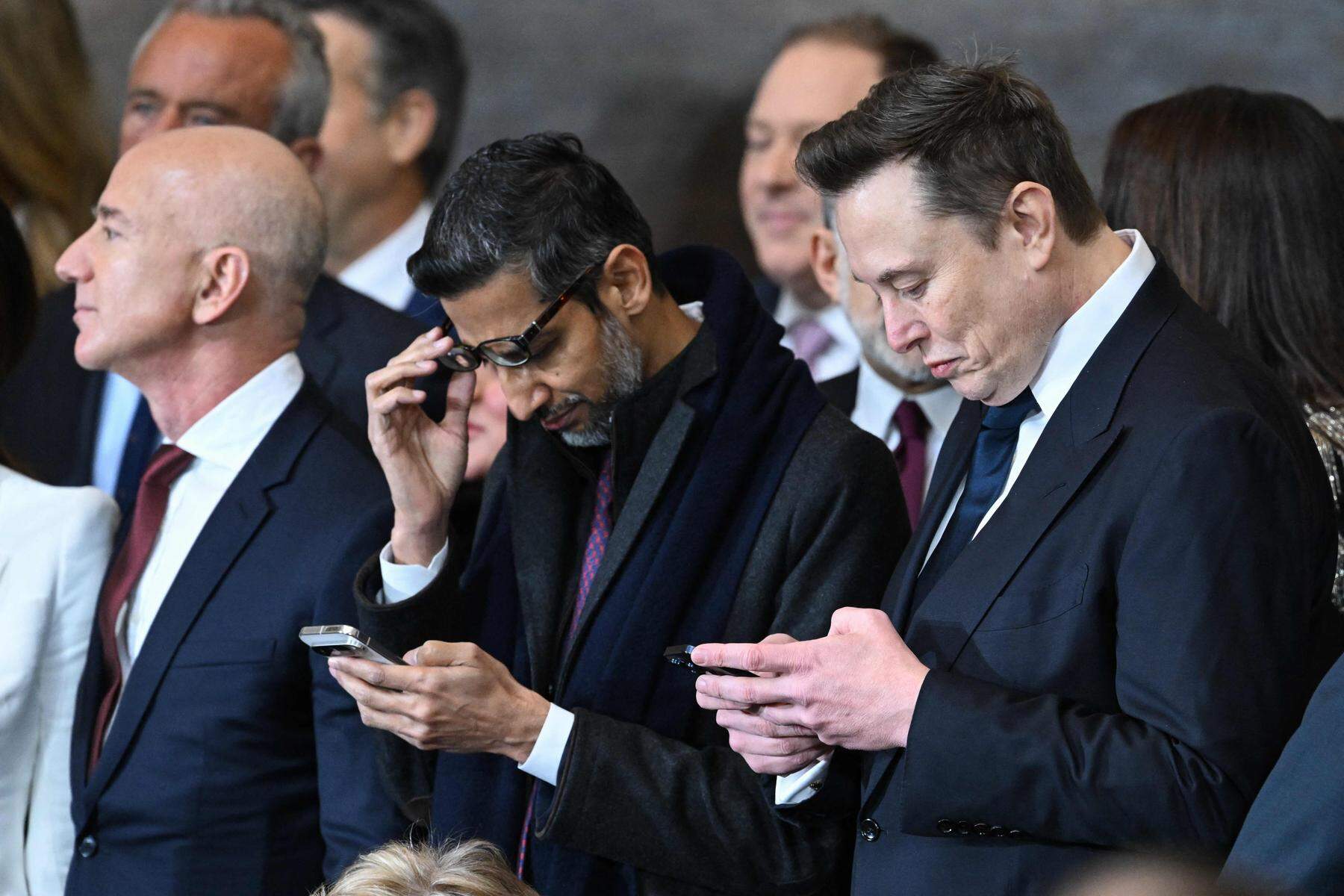 Andere Gäste blickten lieber auf ihr Smartphone. Etwa Google-Chef Sundar Pichai (Mitte) und Tesla-Chef und Trump-Einflüsterer Elon Musk (re.). Amazon-Gründer Jeff Bezos ließ das Handy zumindest auf diesem Foto eingesteckt.