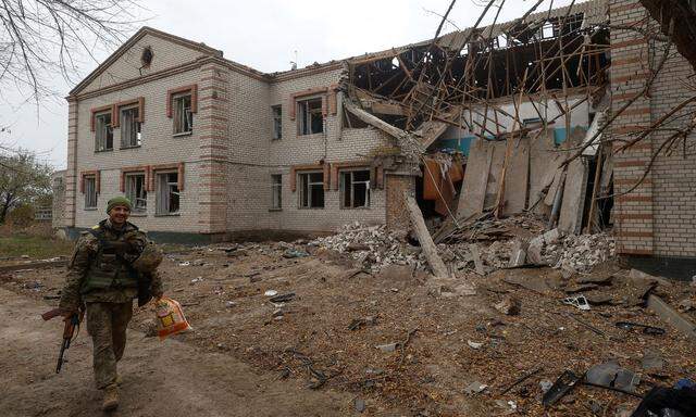 Ukrainian serviceman walks past a building of a kindergarten damaged during a Russian missile attack in the village of Novooleksandrivka, in Kherson region