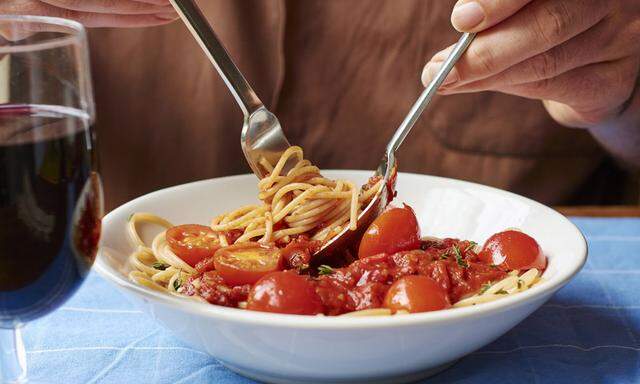 Man eating spaghetti with tomato sauce close up model released Symbolfoto PUBLICATIONxINxGERxSUIxAU