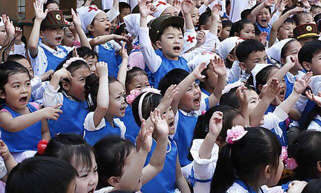 North Korean children cheer during the playing of games on the grounds of Kyongsang Kindergarten in K