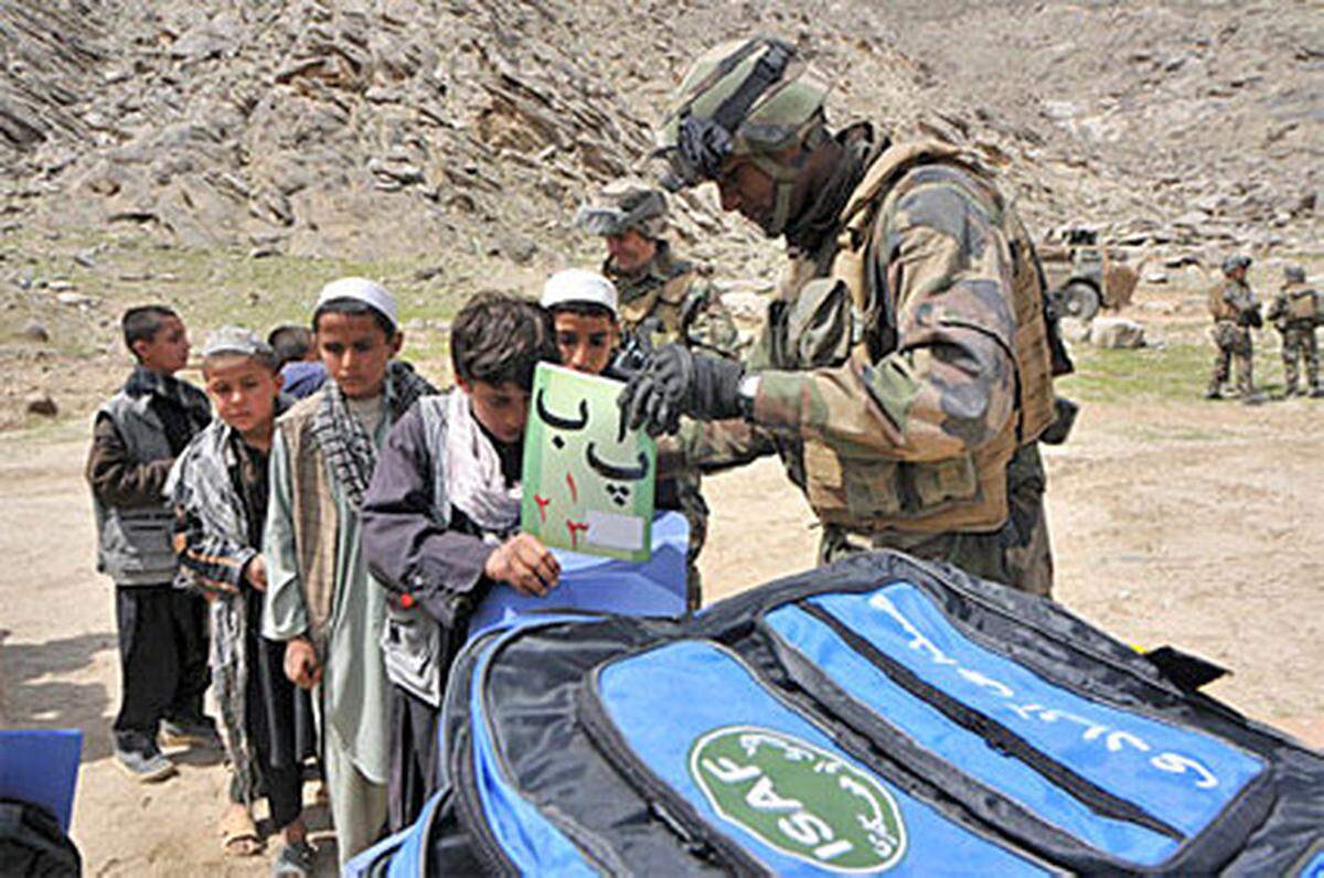 Französischer Soldat von Task Force Tiger beim Verteilen von Hilfsgütern. Jedes Kind bekommt eine Schultasche, Malstifte, eine Schreibtafel, ein Schulheft und ein Paar Flipflops