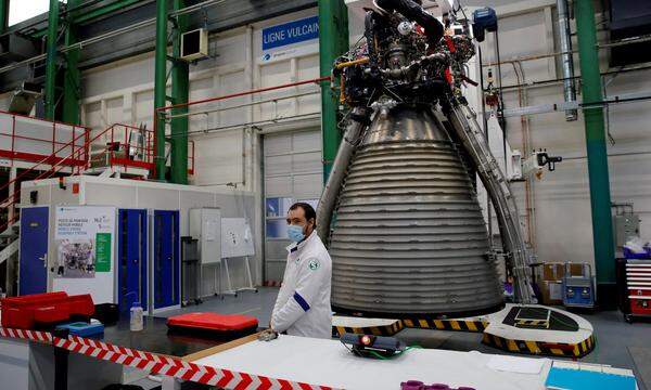 Ein Ingenieur steht vor einem Teil der Trägerrakete Ariane 6.
