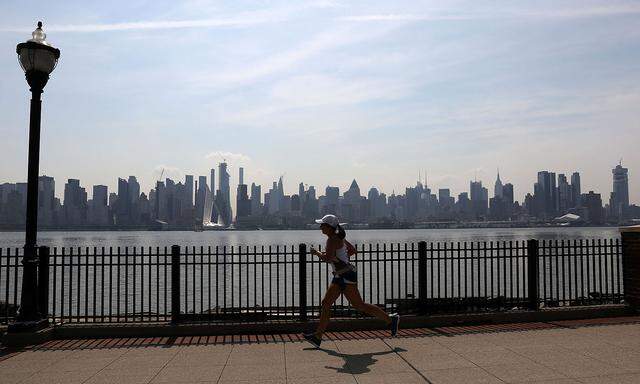 A woman jogs along the Hudson River in front of the New York City skyline as temperatures soared in the northeast U.S., in Weehawken