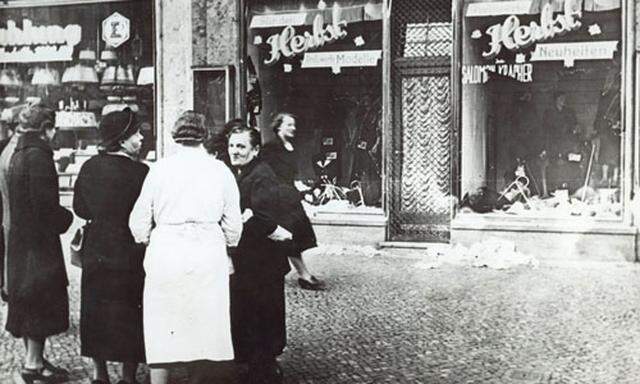 Passanten stehen im November 1938 in einer Stadt in Deutschland vor einem juedischen Geschaeft, dessen Schaufensterscheiben in der Reichskristallnacht am 9. Nov. 1938 zerstoert wurden