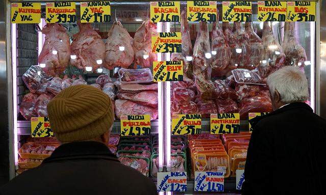 FILE PHOTO: People check prices of a butcher at a bazaar in Ankara