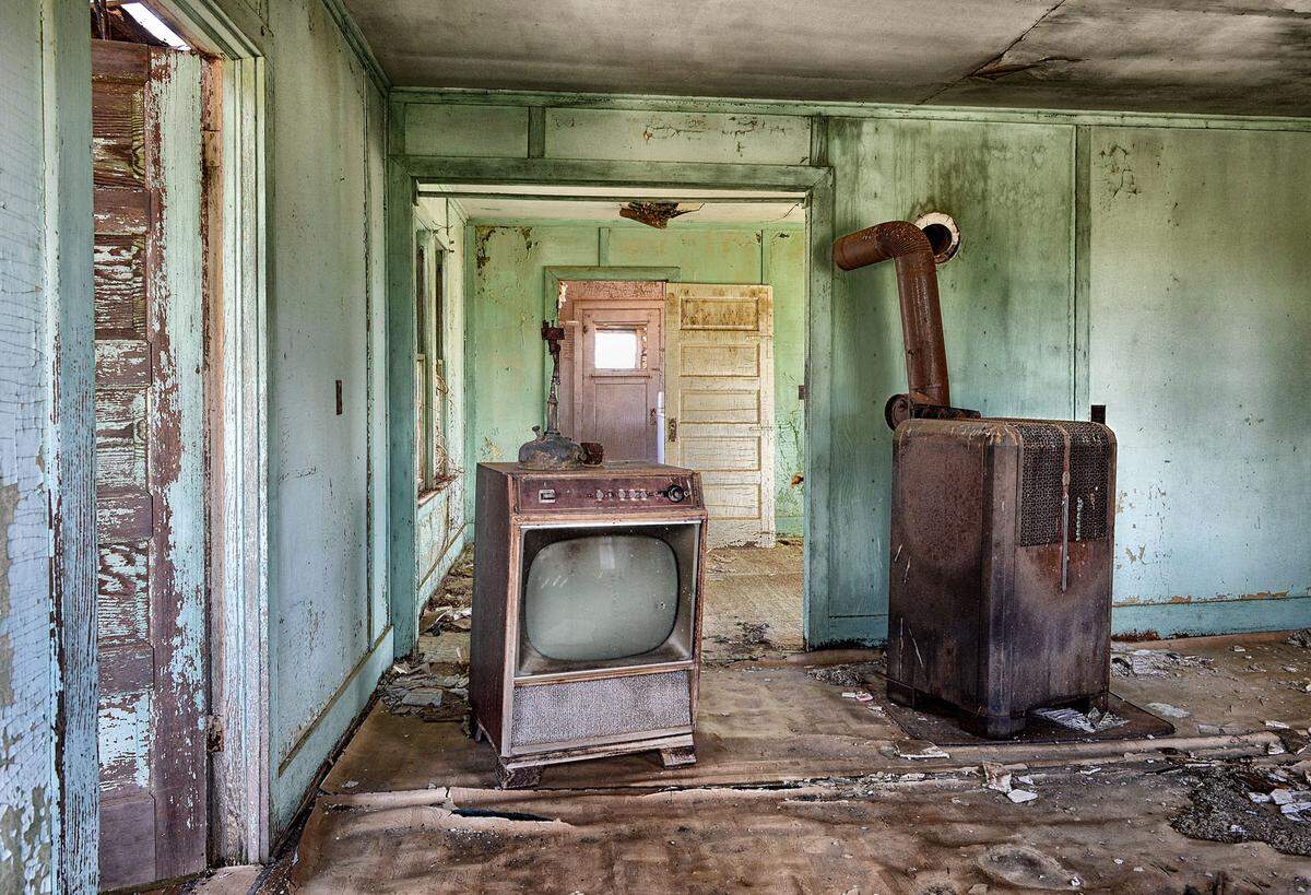 In vielen Bildern liegt eine morbide Schönheit. In diesem ehemaligen Wohnzimmer ist nur ein Ofen und ein Schwarzweiß-Fernseher übriggeblieben.