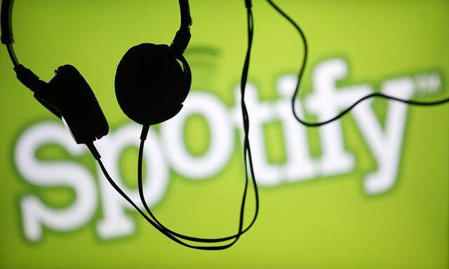 Headsets hang in front of a screen displaying a Spotify logo on it, in Zenica