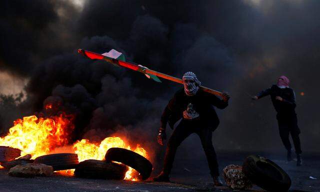 Demonstrator holds a Palestinian flag during clashes with Israeli troops near the Jewish settlement of Beit El near Ramallah