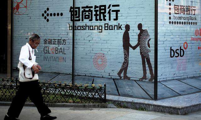 FILE PHOTO: Man walks past a building with an advertisement of Baoshang Bank in Beijing