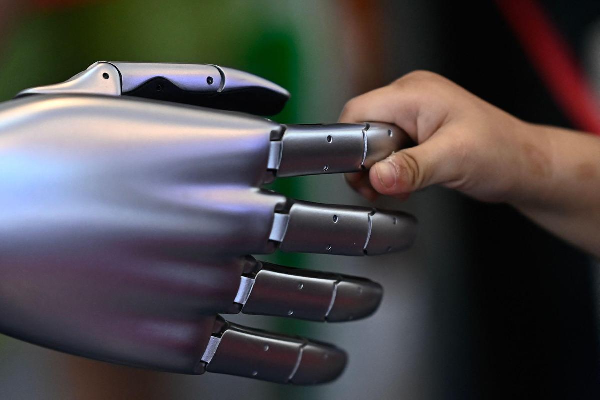 23. Juni. Ein Kind greift den Finger eines Tesla-Roboters bei der World Intelligence Expo 2024 in China. 