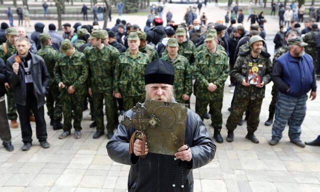A man holds an icon and a cross as pro-Russian protesters gather in front of the regional administration headquarters in Luhansk