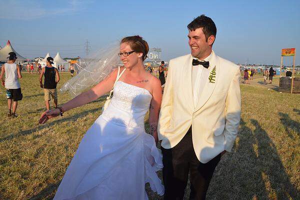 Für Aufsehen sorgt ein Paar, er im tadellosen Hochzeitsanzug, sie im weißen Brautkleid, dessen Saum sich schön langsam an die farblichen Gegebenheiten des Bodens anpasst. Ein Gag? „Sieht das nach einem Gag aus?“, fragt die strahlende Braut und streckt der blöden Frage ihren silber funkelnden Ring entgegen. Bettina und Andreas Schwendenwein haben sich gerade das Ja-Wort gegeben, lassen die Hochzeitsgesellschaft beim Heurigen alleine feiern und sind selbst in die Nickelsdorfer Staubwüste gefahren. Ums Kleid ist es der Braut nicht schade, das zieht man (im besten Fall) eh nie wieder an. Und weiter ziehen die beiden Richtung Blue Stage, stets flankiert von fragenden Neugierigen: „Seid's ihr echt?“