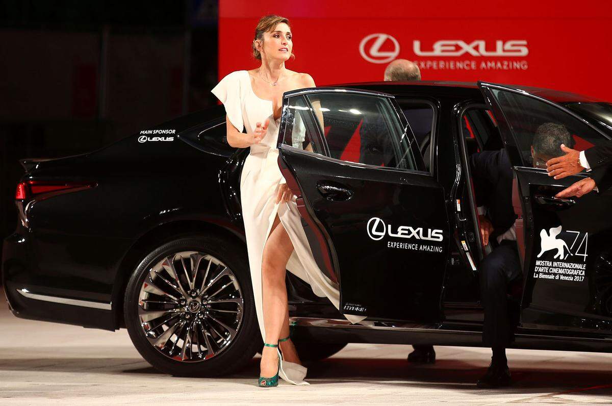 Julie Gayet schwingt sich vorsichtig aus dem Auto, sie trägt ein Kleid mit gefährlichem Schnitt.