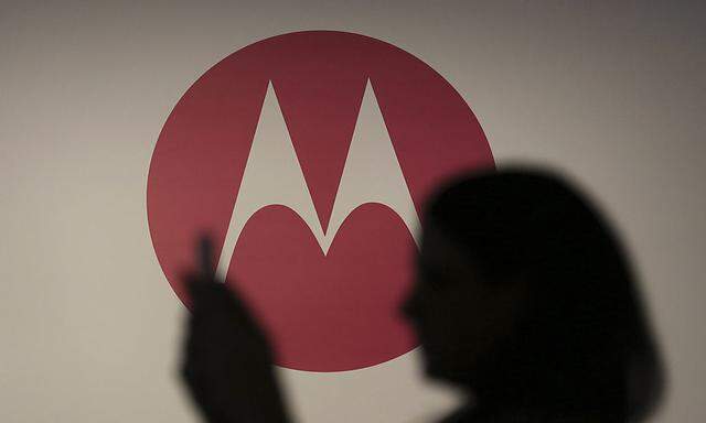 A woman takes a picture in front of a Motorola logo before the worldwide presentation of the Moto G mobile phone in Sao Paulo