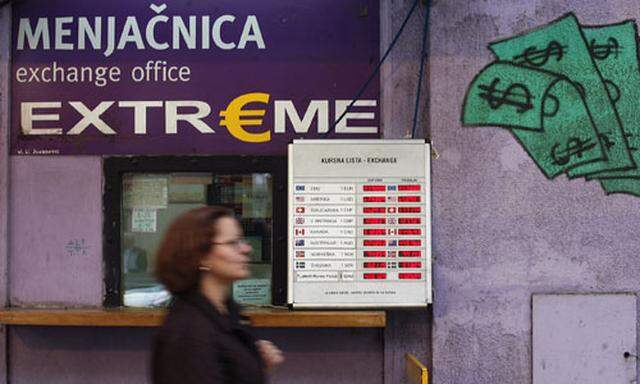 A woman walks past a board of a currency exchange office in central Belgrade