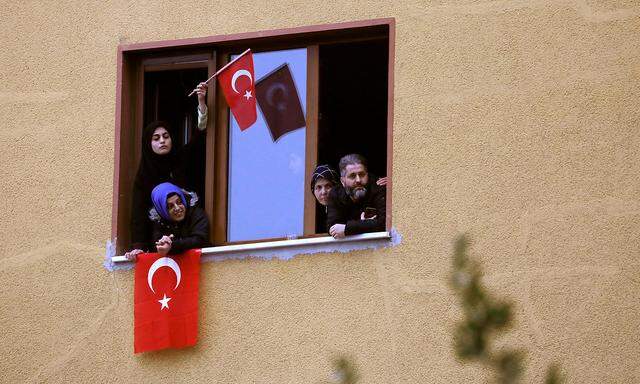 Supporters of Turkish President Tayyip Erdogan look out of a window during a rally for the upcoming local elections in Istanbul