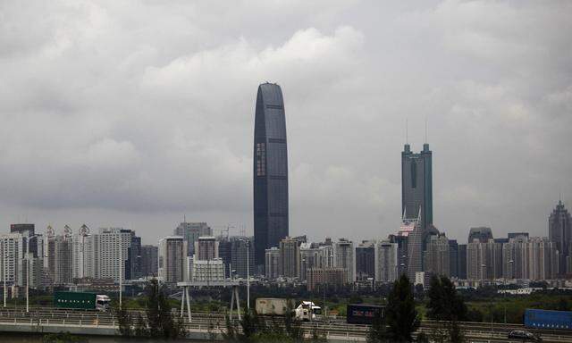 Container trucks cross a bridge in front of the Kingkey 100 building in Shenzen