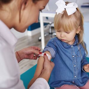 Doctor applying band-aid on girl s arm in medical practice model released Symbolfoto property released PUBLICATIONxINxG