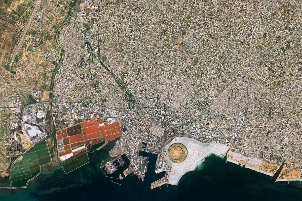 Spinnennetz am Wüstenrand: Sfax, mit 330.000 Einwohnern zweitgrößte Stadt Tunesiens, fällt im Satellitenbild durch seinen konzentrischen Aufbau auf. Vom alten Zentrum mit seinen kleinen Gebäuden und engen Gassen verlaufen die Hauptstraßen sternförmig nach außen, wo sie spinnennetzartig durch Ringstraßen verbunden sind. Gut zu sehen ist auch die allmählich nach außen lockerer werdende Bebauung. In der kreisförmigen Struktur am Meeresufer wird eine ausgedehnte Parkanlage errichtet. Sie liegt im Stadtentwicklungsgebiet Taparura, das nach Fertigstellung 50.000 Bewohner aufnehmen soll.