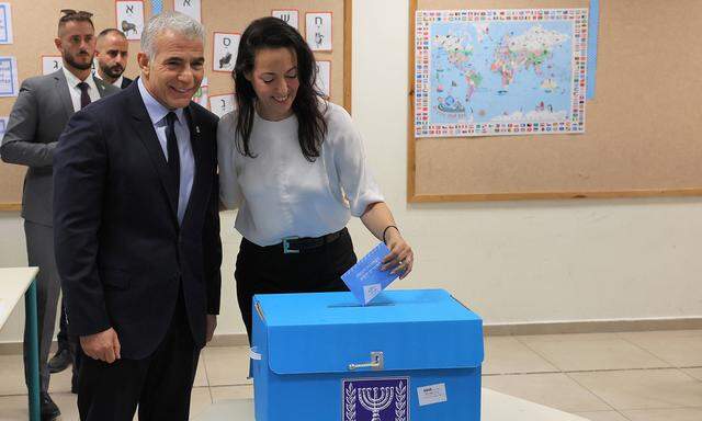 Israeli Prime Minister Yair Lapid smiles to the cameras as his wife Lihi casts her vote at a polling station in Israel