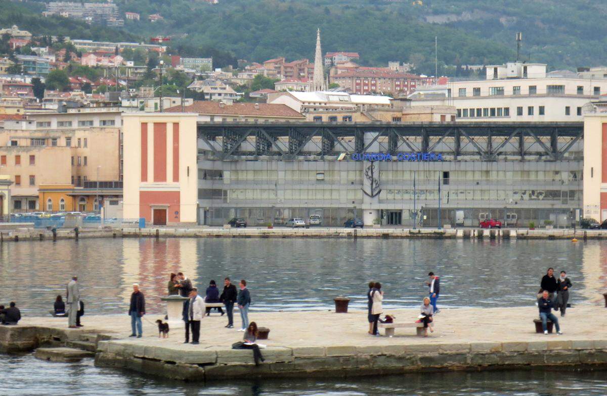 Am „Molo audace“, dem steinernen Pier im Zentrum Triests. Er trägt den wilden Namen des italienischen Zerstörerschiffs, das 1918 hier anlegte und die Stadt unter dem Jubel der Bevölkerung (jedenfalls der Italiener) von den Österreichern befreite, die immerhin seit 1382 vorherrschten