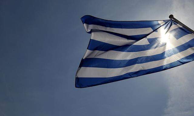 A Greek flag flies in the wind at a park in central Athens