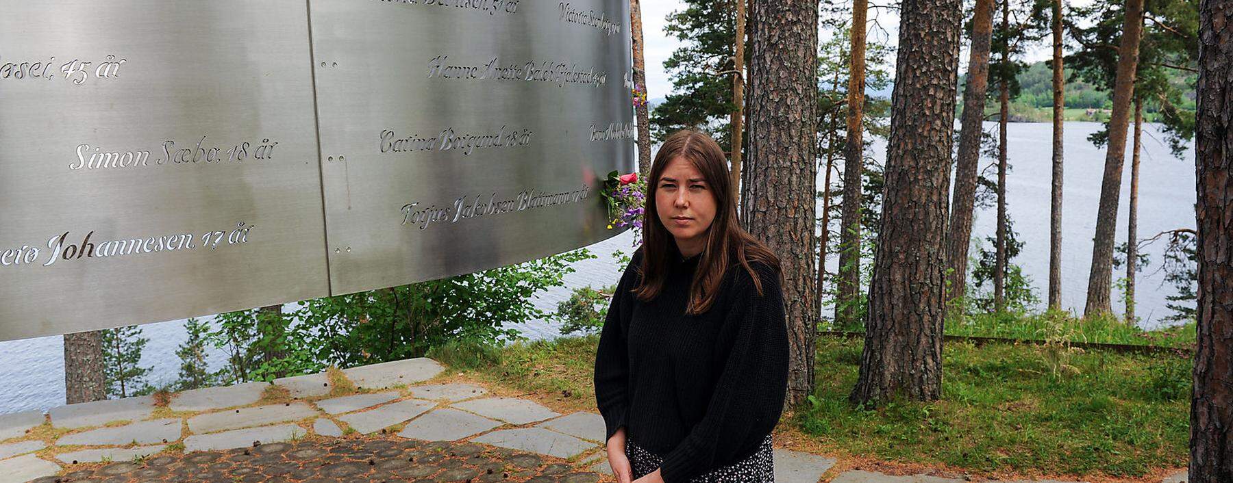 Eine Überlebende des Attentats vor einer Gedenktafel für die Ermordeten.