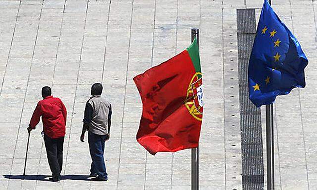Two men walk under the flags of Portugal and the European Union, right,  Thursday, July 21, 2011, in 