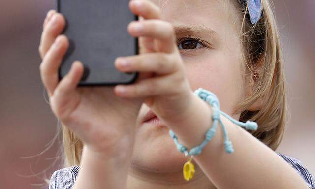 A child takes pictures with a mobile phone as Pope Francis leads the Angelus prayer at the Vatican