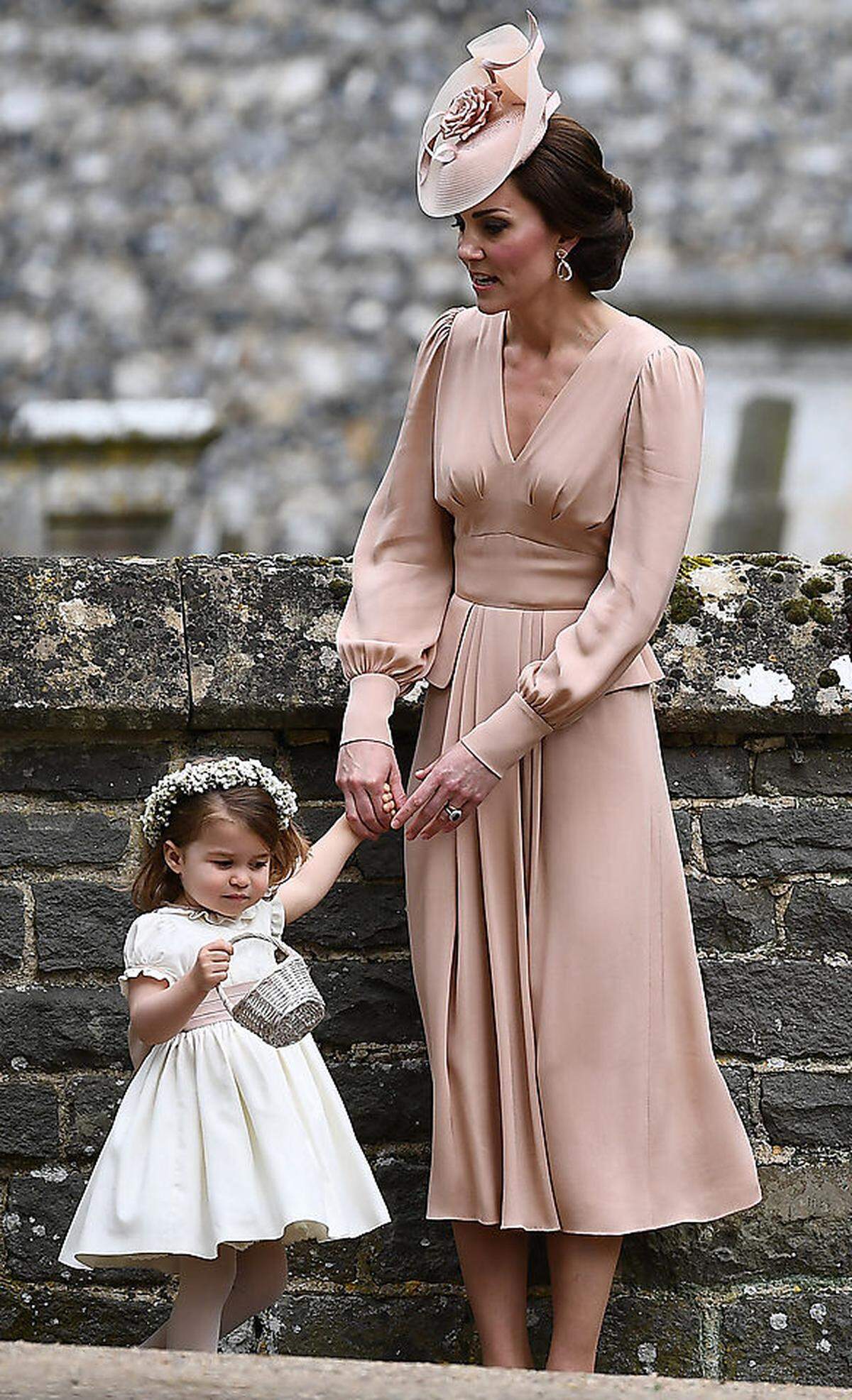 Die Fähigkeit der Kleidermacher der Herzogin von Cambridge, alle Teile eines Outfits derart eintönig einzufärben, sei als positives Talent erwähnt, das offensichtlich auch schon bei Kleidern der kleinen Prinzessin Charlotte angewandt wird. Kates Hut stammt von Jane Taylor, die Schuhe von Gianvito Rossi, die großen, pinken Ohrringe von Kiki McDonough.