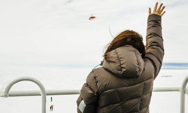 Nicole De Losa, a passenger on board the MV Akademik Shokalskiy waves to a helicopter sent from the Chinese icebreaker Xue Long (Snow Dragon) to assess ice conditions around the Russian Ship, in Antarctica