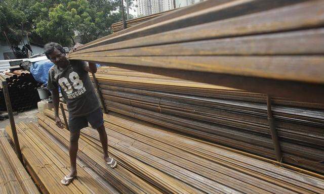 A worker loads iron rods in a truck at an iron and steel market in an industrial area in Mumbai