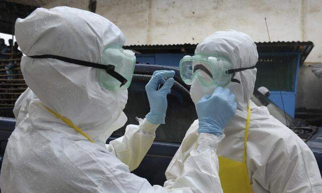 Health workers wearing protective clothing prepare themselves before to carrying an abandoned dead body presenting with Ebola symptoms at Duwala market in Monrovia