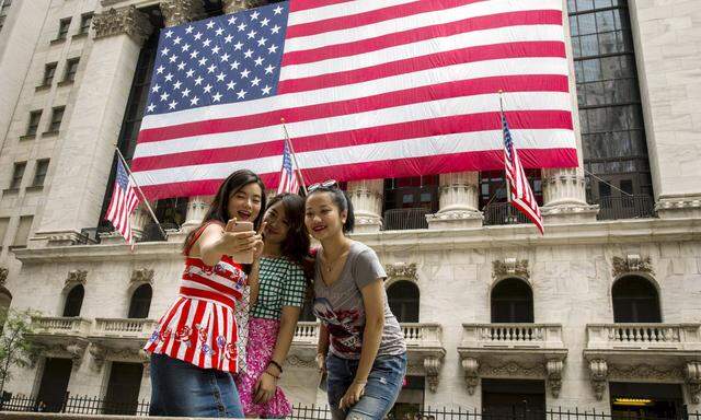 Chinese tourists take photographs of themselves outside of the New York Stock Exchange shortly after the opening bell in New York