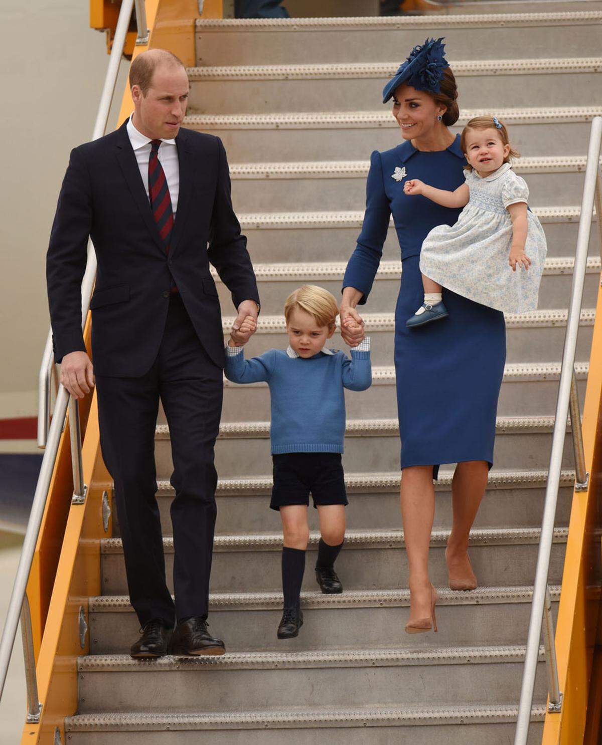 Mutter Kate trägt bei den Ankunft in British-Columbia ein bemerkenswert enges blau-lila-farbenes Kleid und einen kleinen Hut.