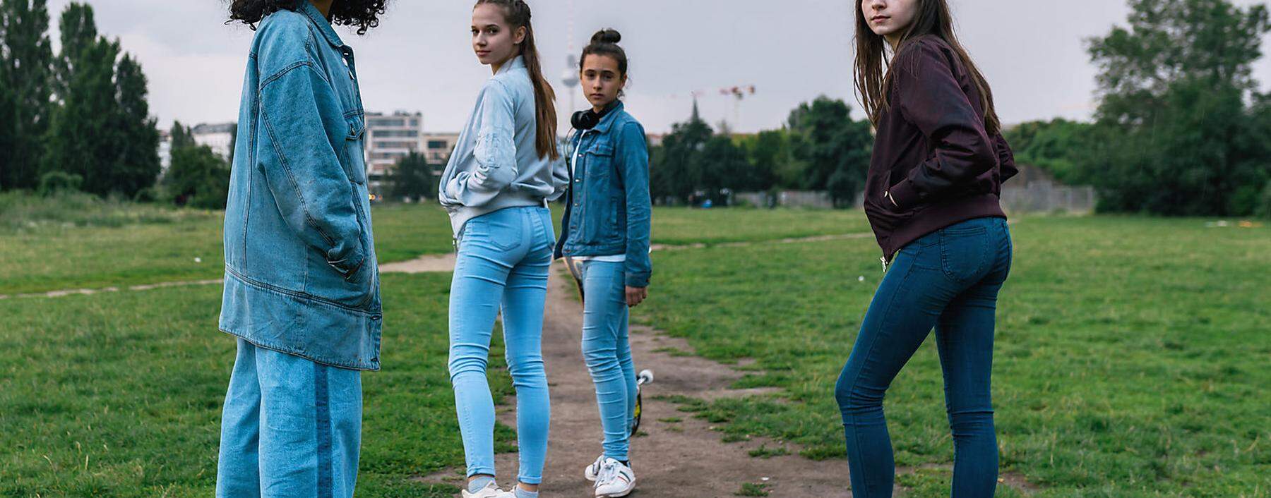 four teenage girls walking outdoors in park