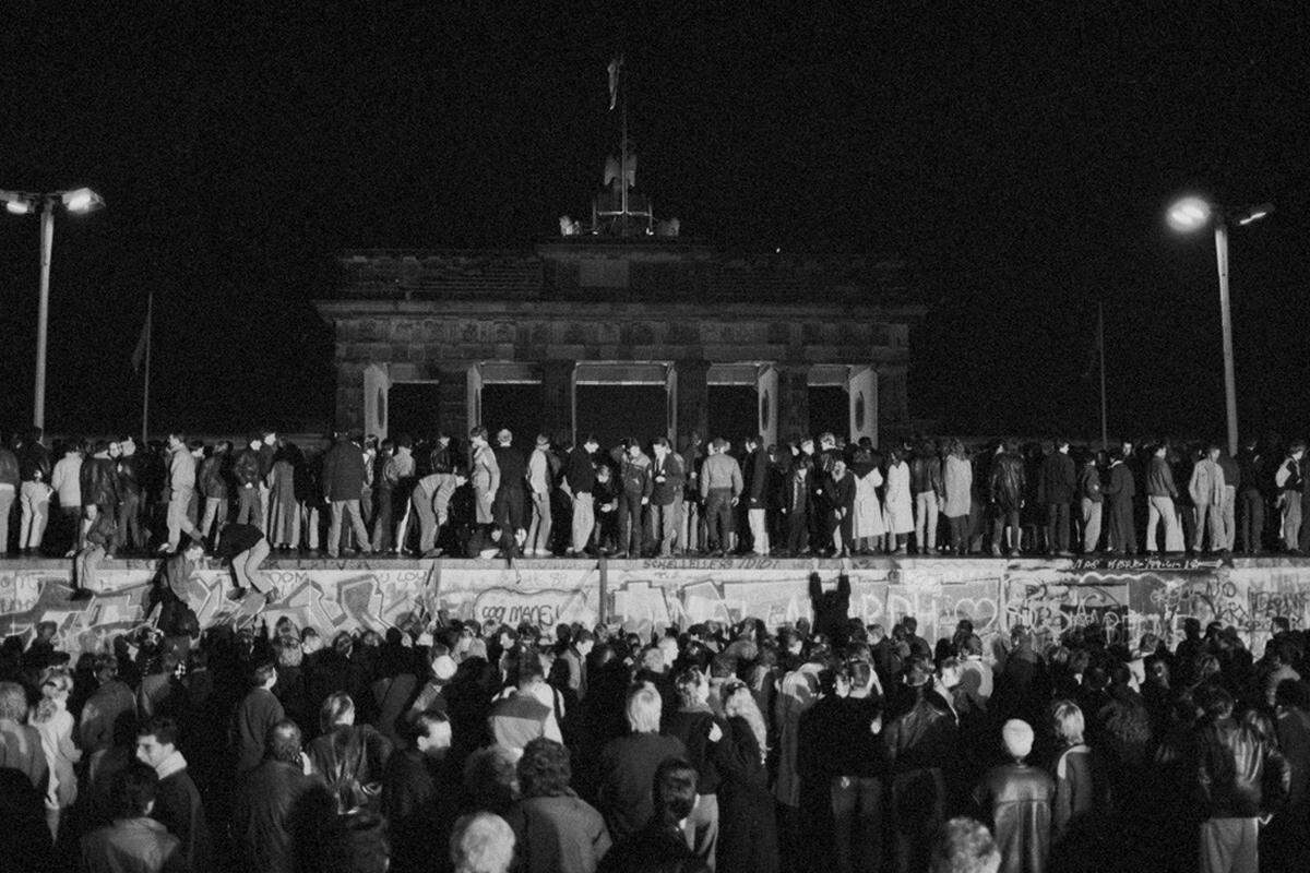 9. November 1989: Ost- und Westberliner feiern an und auf der Mauer beim Brandenburger Tor die Öffnung der DDR-Grenzen. Das Brandenburger Tor stand während der Teilung Berlins im Sperrgebiet.