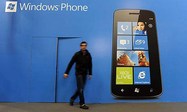 A man walks past a banner of a Windows phone at the Mobile World Congress, the worlds largest mobile