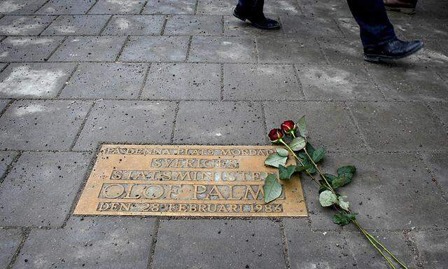 Pedestrians walk past a plaque marking the location where Swedish Prime Minister Olof Palme was killed 25 years ago in Stockholm