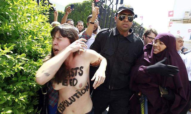 Police officers detain an activist from the women's rights group FEMEN during a protest in front of Tunisia's Ministry of Justice in Tunis